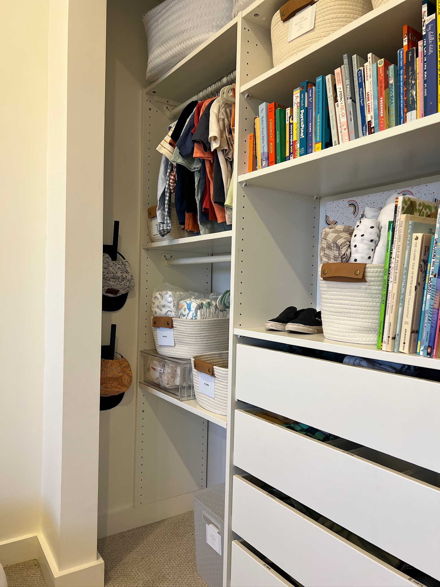 Alternate view of an organized children's closet with baskets, books, and hanging clothes.