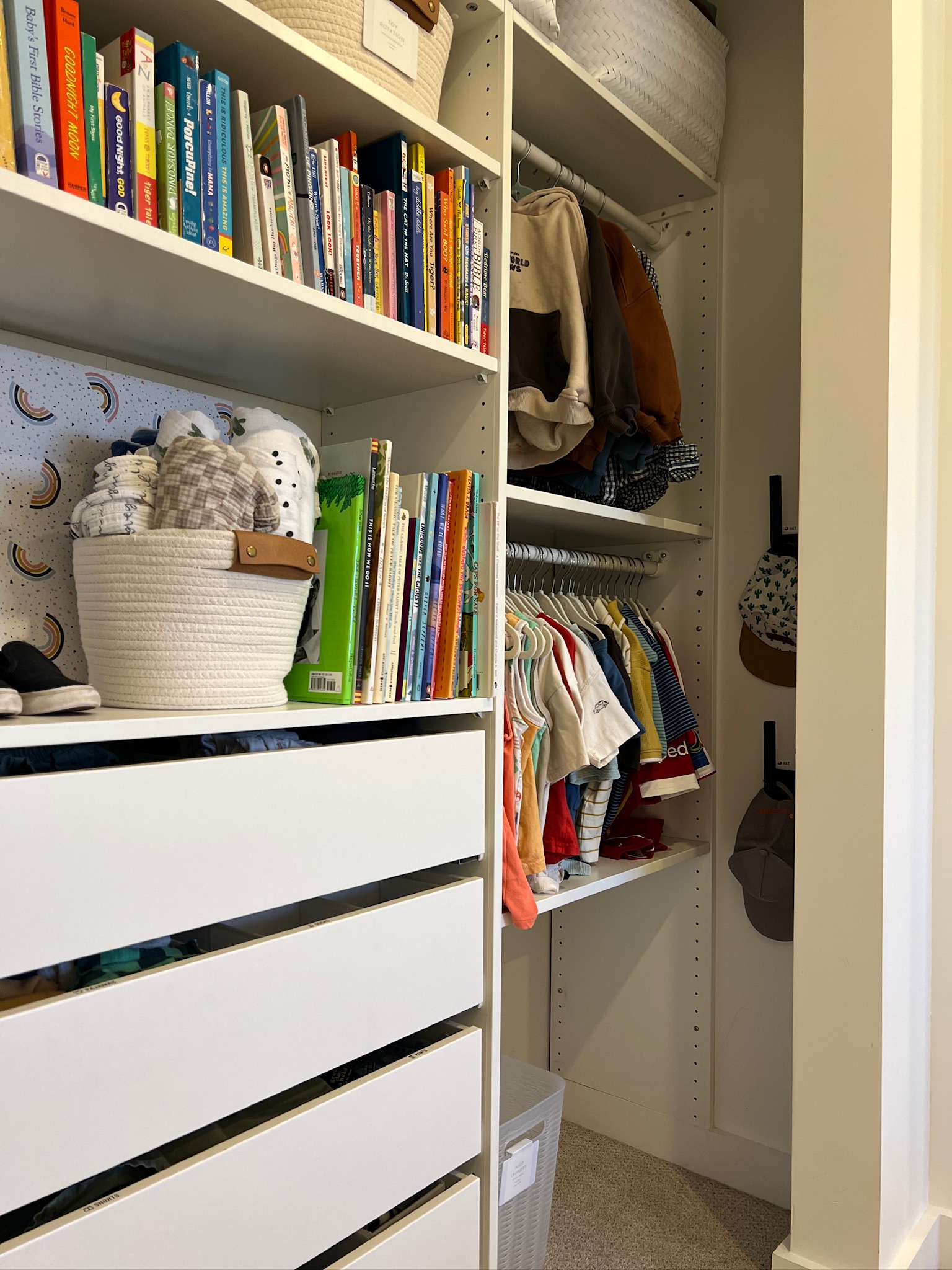 Organized children's closet with labeled drawers, books, baskets, and hanging clothes.